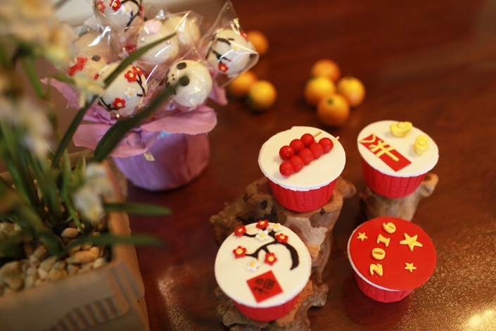 four cupcakes with icing sitting next to a plant