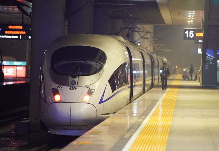 a Chinese train sits at platform number 15 as a conductor walks beside it