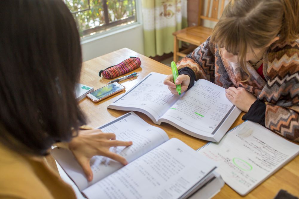 a student marking a textbook with a green highlighter