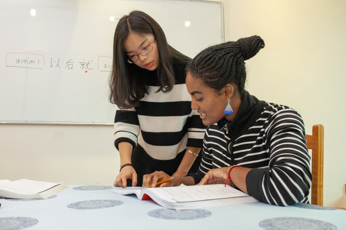 a CLI teacher teaching a student in a striped shirt to say "no" in Chinese