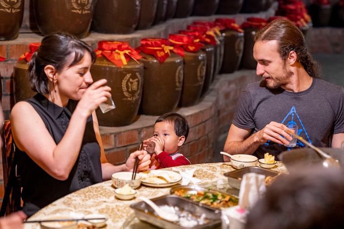 two CLI students and a small Chinese child eating dinner