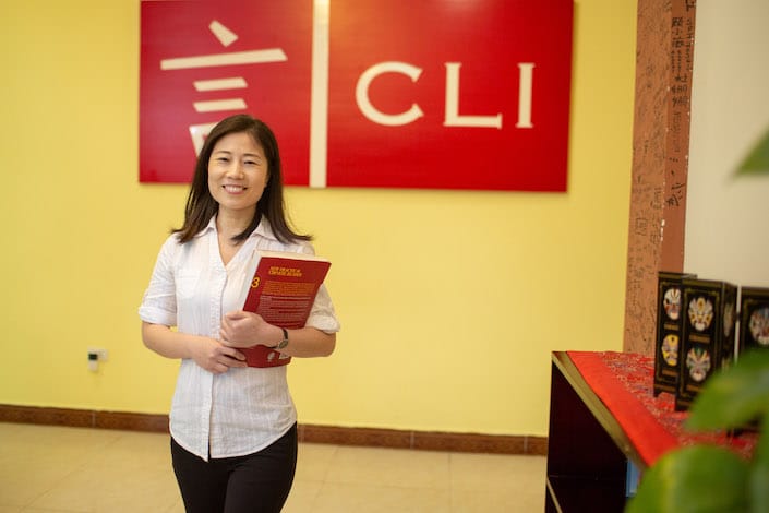 chinese teacher standing in front of school logo
