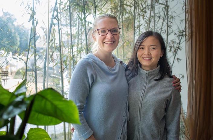 student and teacher in china with plant in foreground and bamboo in background